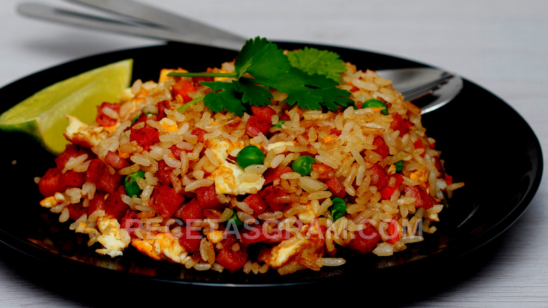 imagen de plato servido de arroz con guisantes y tocino decorado con hojas de perejil, de la receta de arroz navideño con tocino