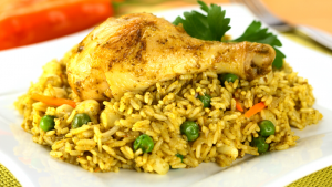 Plato servido de arroz amarillo, con pollo y guisantes verdes, decorado con hojas de perejil, de la Receta de Arroz con Pollo a la Chorrera